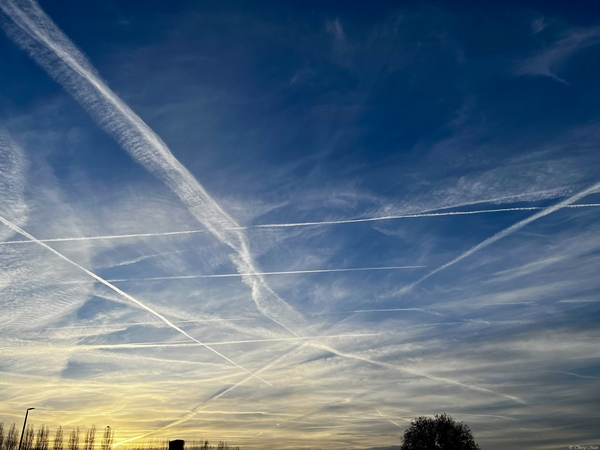 Traînées de condensation laissées par les avions dans un ciel bleu intense au lever du soleil Traînées de condensation laissées par les avions dans un ciel bleu intense au lever du soleil